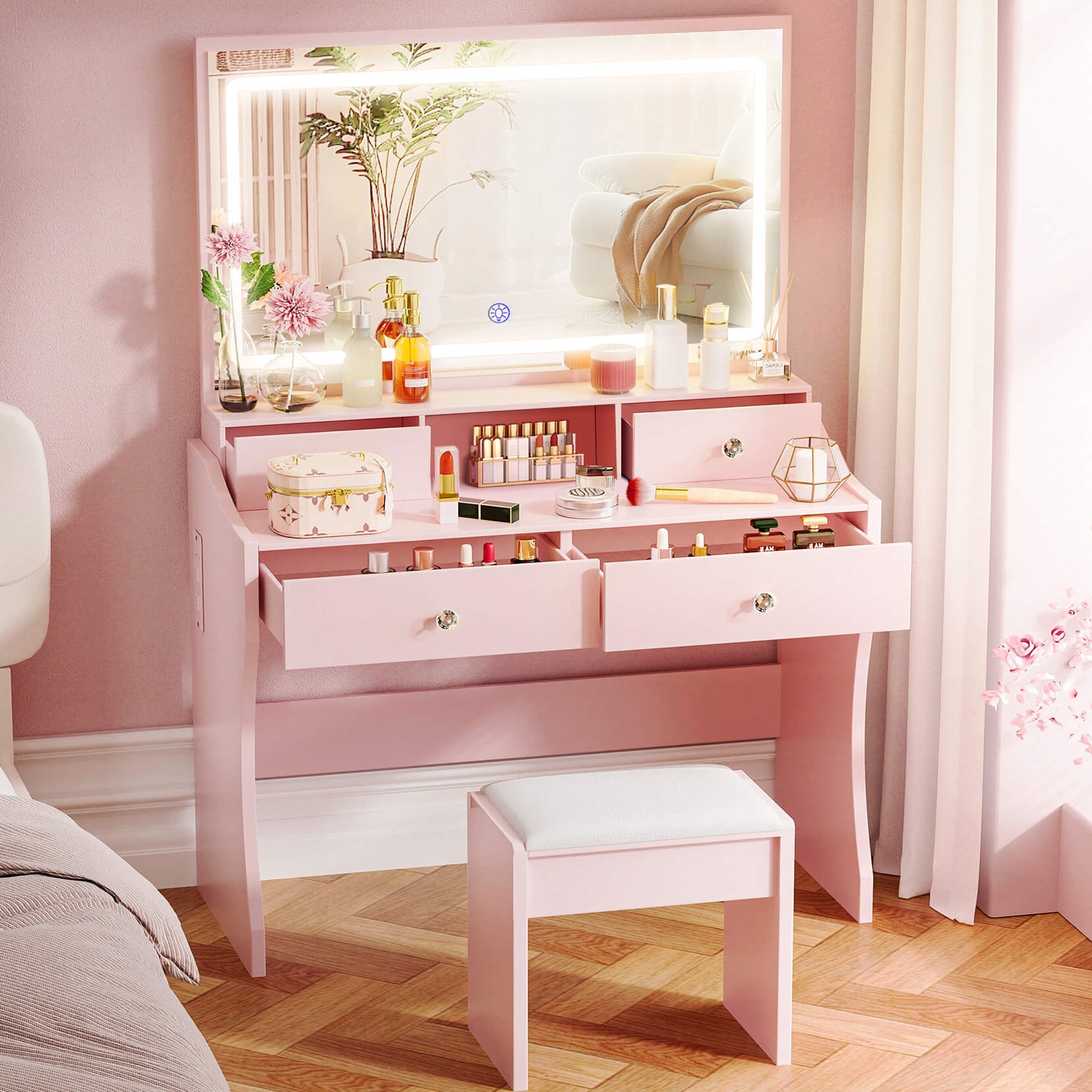 Pink vanity table with mirror and various items in a room with pink walls and wooden floor.