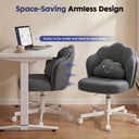 Ergonomic grey armless office chair with petal design and a smiling cloud cushion, shown easily sliding under a white adjustable desk, highlighting space-saving features.
