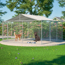 Large galvanized chain link playpen with waterproof cover and secure lock, set in a backyard with green grass and trees, containing two dogs and metal food bowls inside.