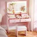 Pink vanity table with mirror and various items in a room with pink walls and wooden floor.