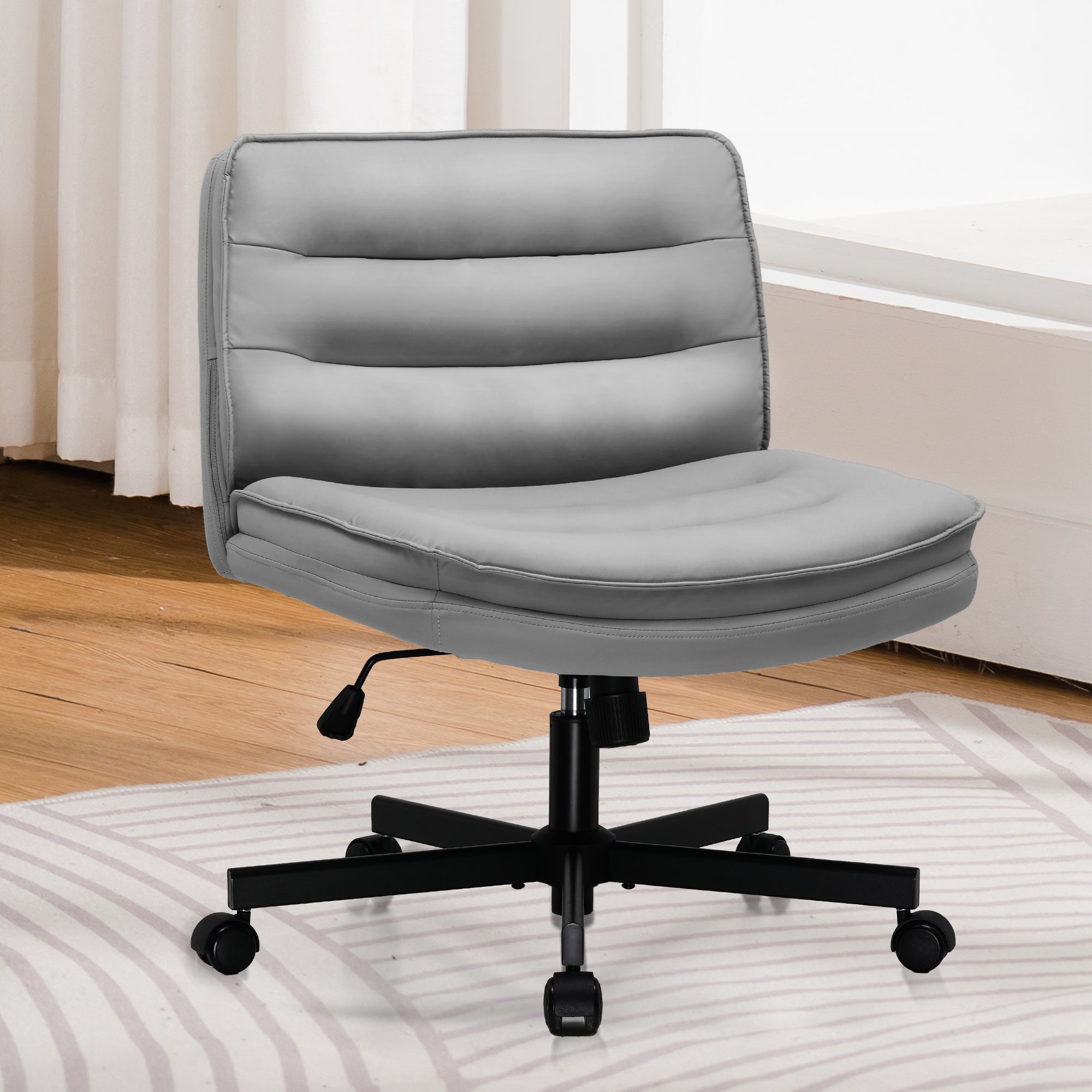 Gray ergonomic armless office chair with adjustable height, low back support, and black caster wheels on a striped rug in a bright room with wooden floors and white curtains.